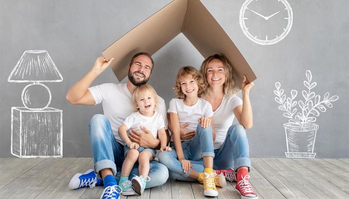 Family sitting on floor with moving box in new home through mortgage lender.