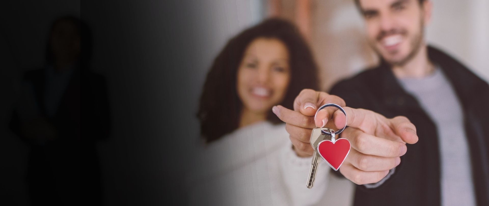 Happy couple in new home holding key ring with red heart and house key bought through the best mortgage lender in Denver.