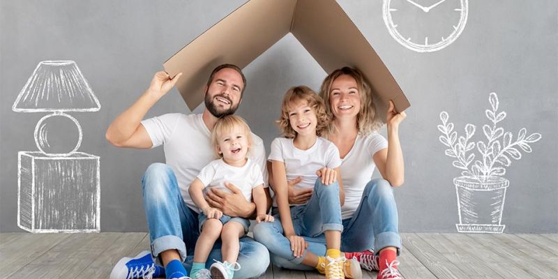 Family sitting on floor with moving box in new home through mortgage lender.